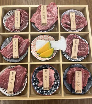 아홉 칸 나무 상자에 접시마다 담은 한우 — 안창살·살치살·새우살·갈비살·꽃등심·안심·치마살 이름표, 가운데 칸은 새송이버섯과 단호박